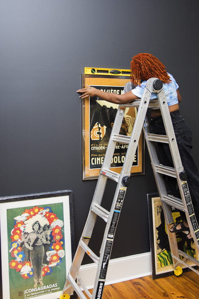 alexa hanging art on wall after she measure rooms for decorating project