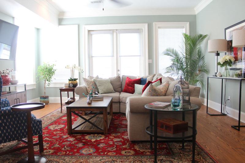 red and blue transitional living room | whitney j decor | new orleans homes | nola decor | red pillows | green walls | sherwin williams oyster gray on the walls | vintage red rug | pottery barn sectional | convertible coffee table | new orleans interior designer | new orleans decorator | new orleans blogger | nola interior designer | nola decorator | nola blogger