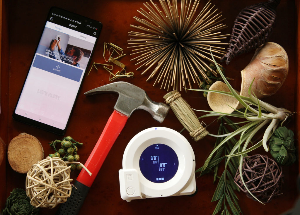 flatlay of the Plott app and cubit tool with other decor, styling around a vintage piano