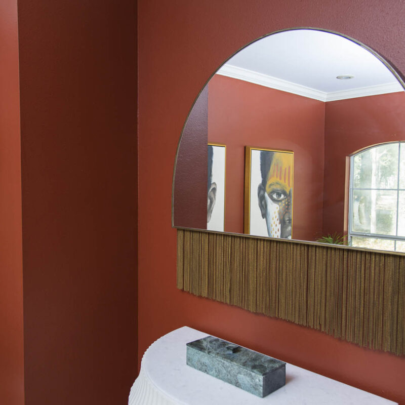 photo of mirror with gold tassel detail hanging over white dresser | bold red sitting room
