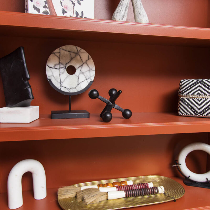 closeup photo of home accessories on red-orange bookcase | bold red sitting room
