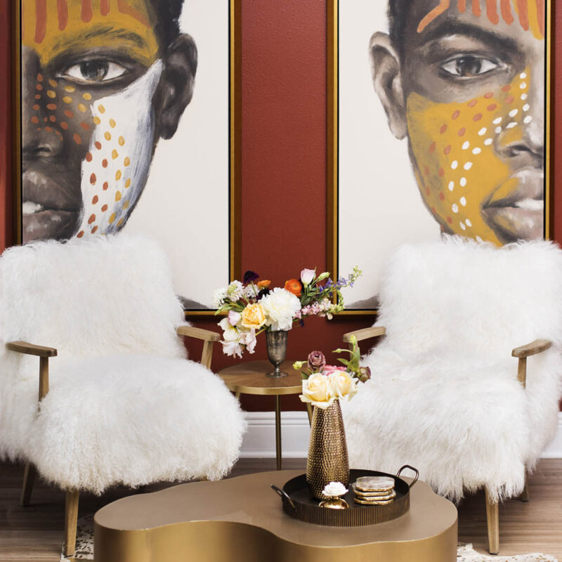photo of sitting area with two club chairs covered in faux fur, painted coffee table and two large graphic art pieces in the background | bold red sitting room
