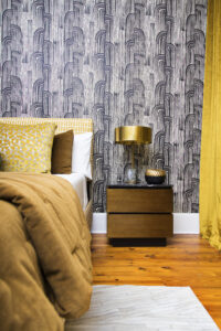 Modern bedroom with black and cream Kelly Wearstler Crescent wallpaper, gold metal nightstand, gold metal shade marble lamp, and warm layered bedding designed by Whitney J Decor