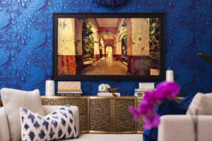 Luxe mauve bedroom with canopy bed, metallic wall art, plush mauve chairs, abstract rug, and a Frame TV displaying artwork, styled by Whitney J Decor.