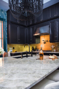 Bold blue kitchen with warm wood and black painted cabinets, brass accents, and layered decorative styling by Whitney J Decor.